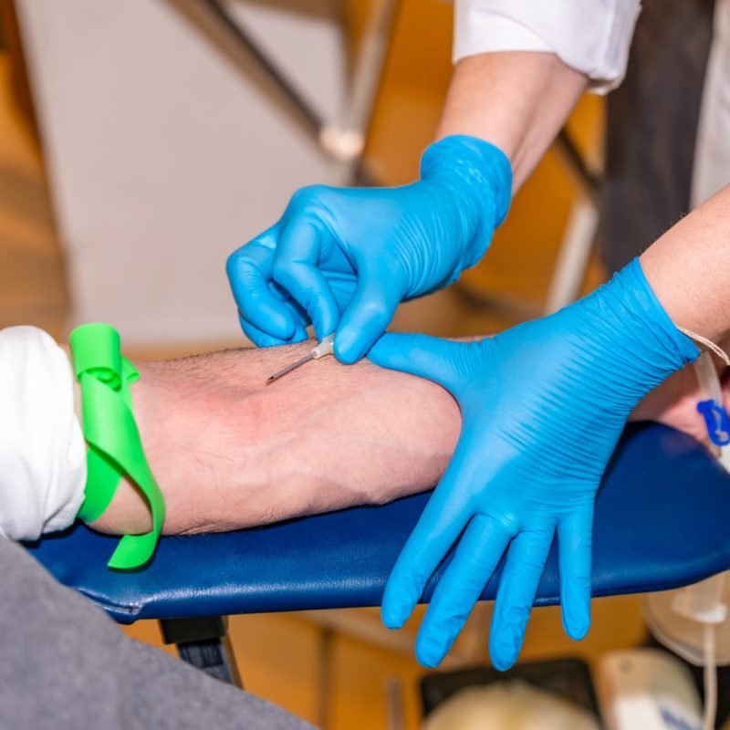 Close-up of an unrecognizable nurse puncturing the vein of a blood donor